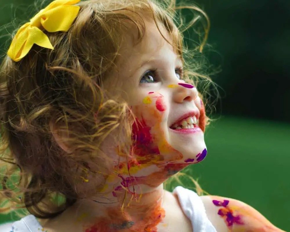 A little girl covered with paint
