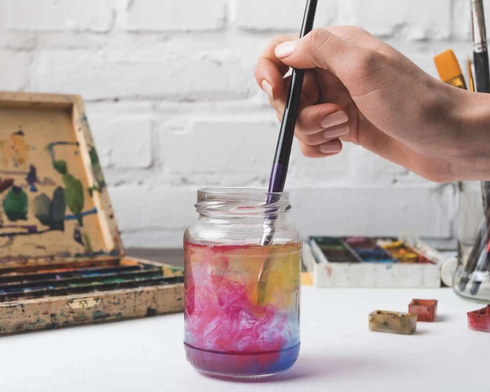 A jar with paint water and a paint brush