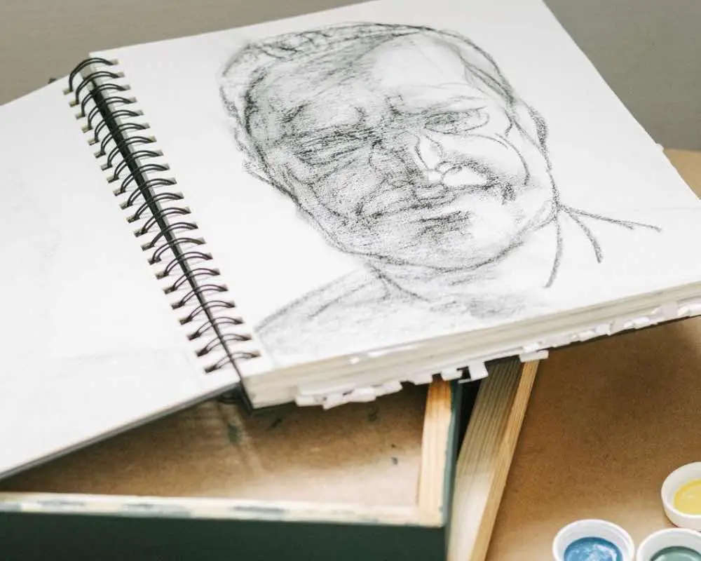 An open sketchbook with the drawing of a man's face