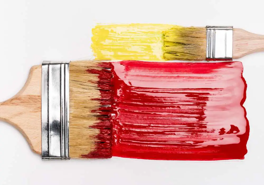 Paint brushes covered with thick red and yellow paint