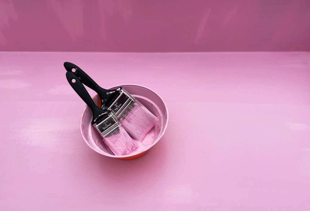 Two paint brushes dipped in pink paint
