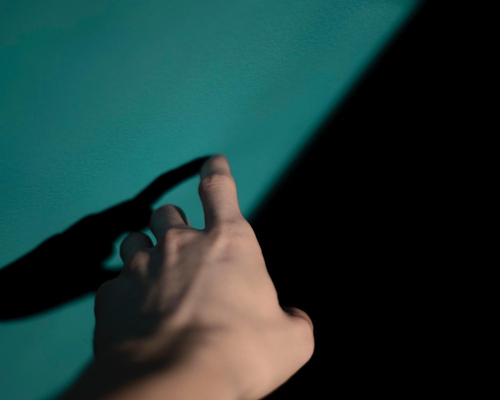 A hand finger pointing toward cyan/aqua color