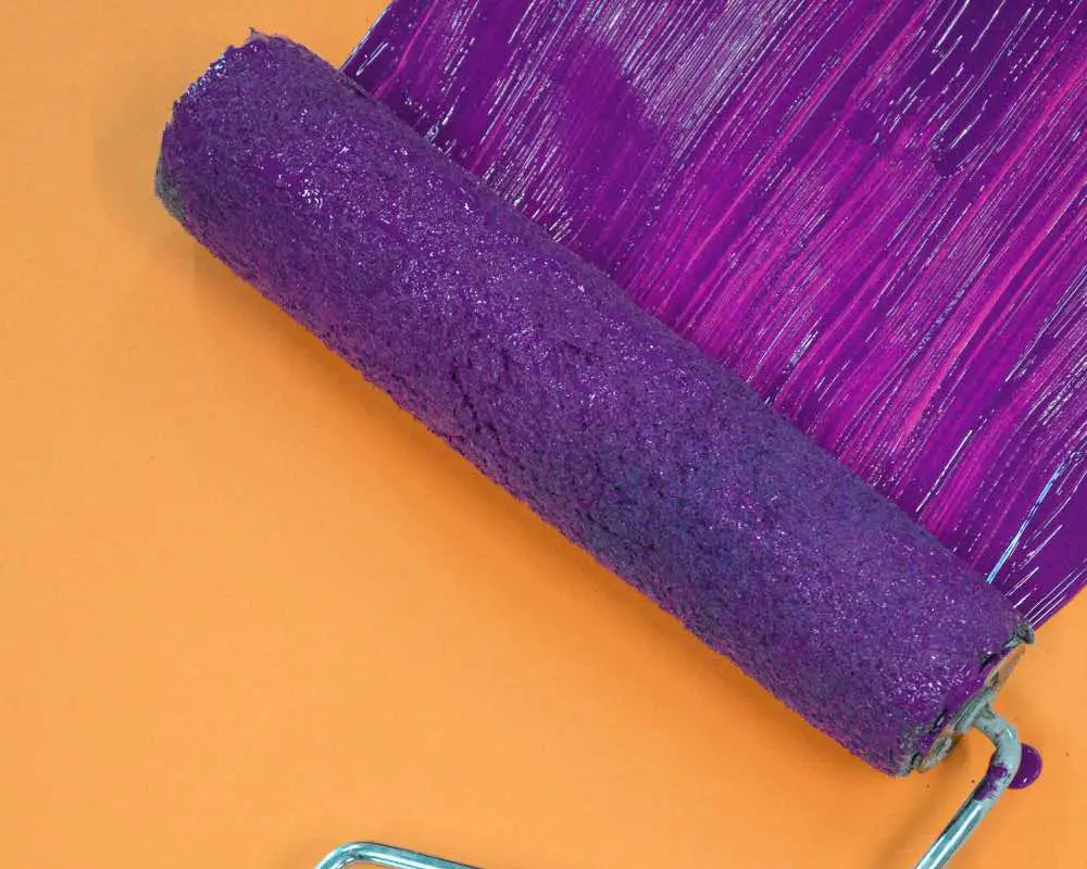 A roller with purple paint on it, sliding over a surface