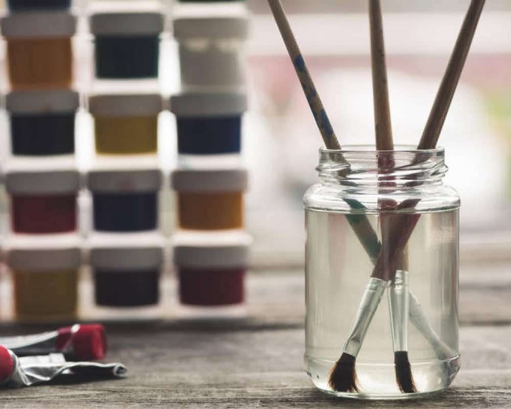 A jar with paint brushes immersed